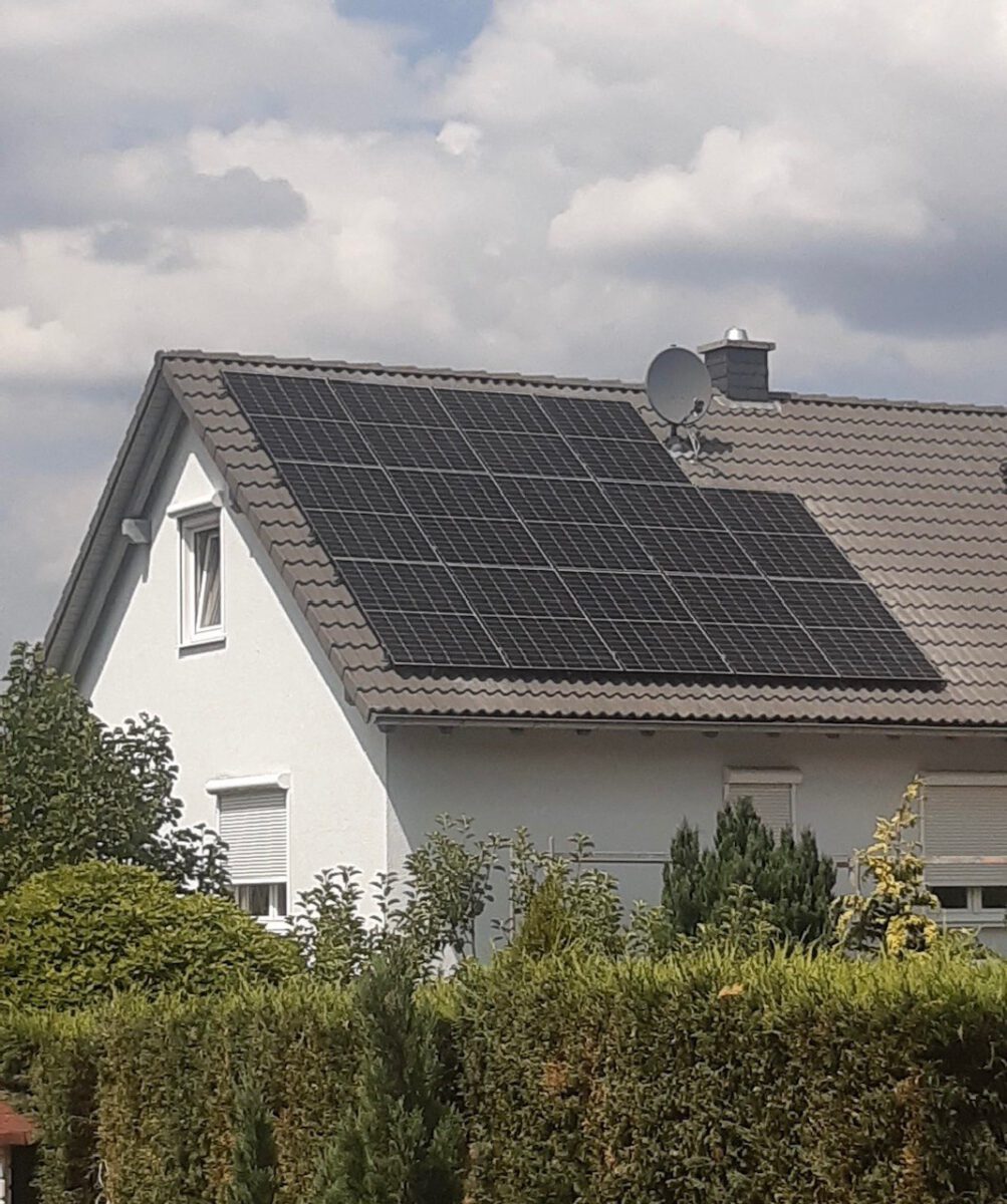 Einfamilienhaus mit einer großflächigen Photovoltaikanlage auf einem grauen Ziegeldach.